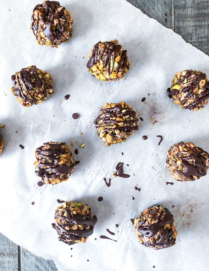 Fig and Pistachio Blissful Bites drizzled with chocolate on parchment paper