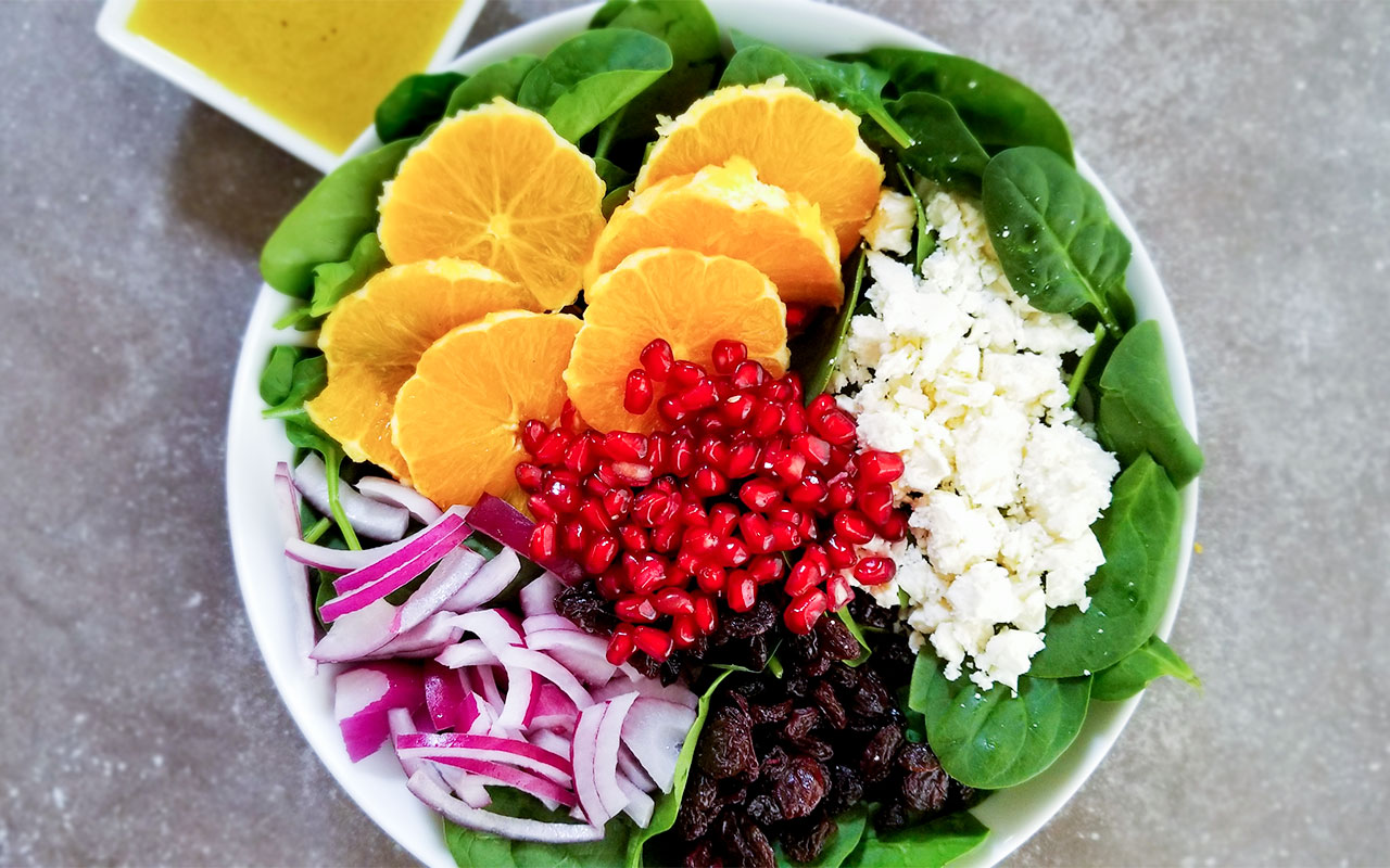 Fall pomegranate salad in a bowl with dressing on the side