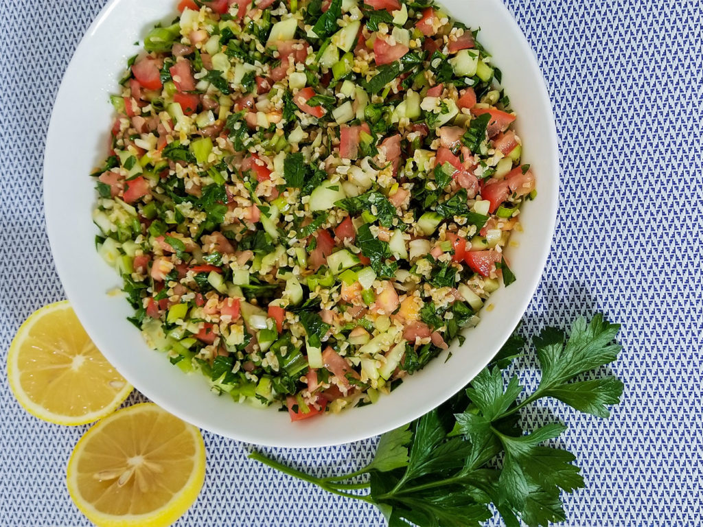 Tabbouleh (Tabouli) in a large bowl with lemons on the side