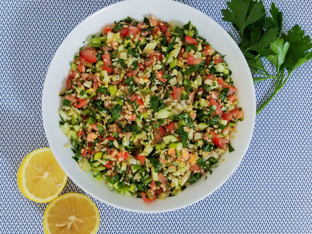Tabbouleh (Tabouli) in a large bowl with lemons on the side