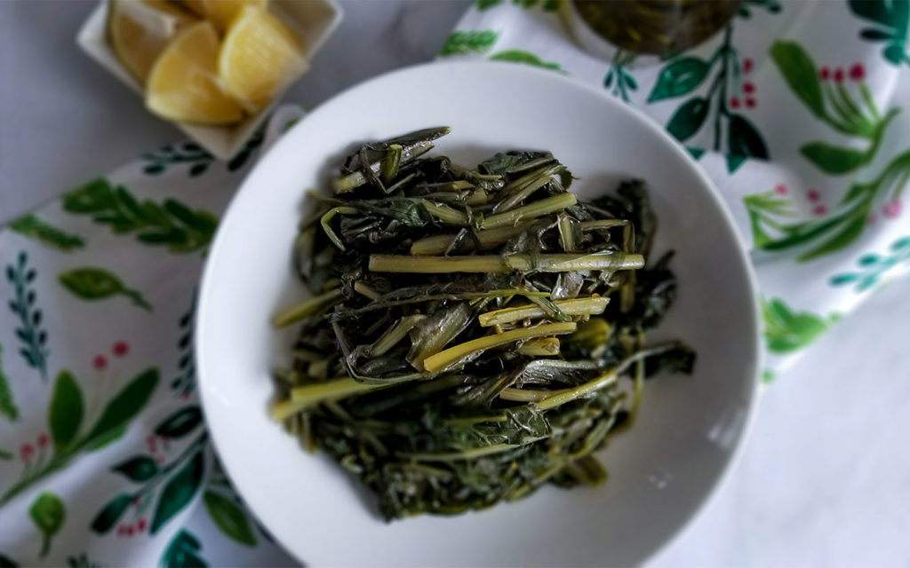 Horta Greek Greens on a bowl with lemon wedges on the side