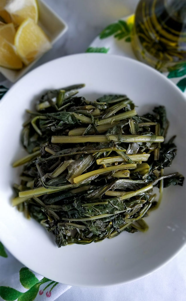 Horta Greek Greens on a bowl with lemon wedges on the side