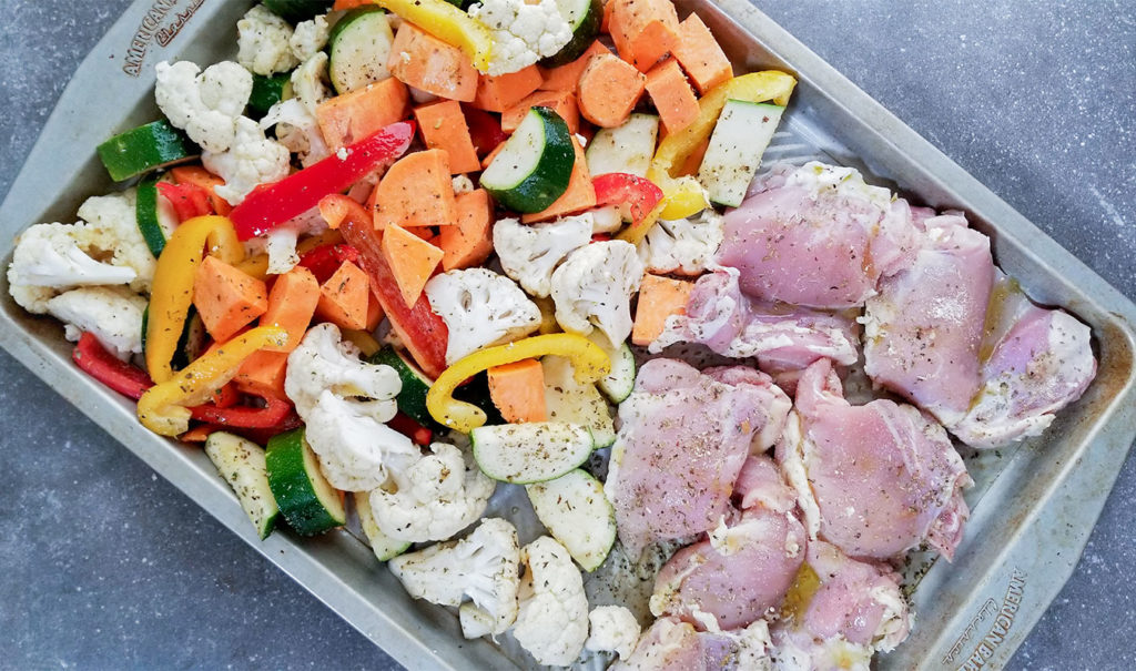 raw vegetables and chicken on a sheet pan