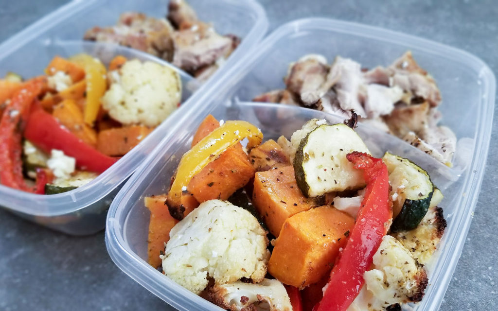 baked vegetables and chicken divided into plastic containers