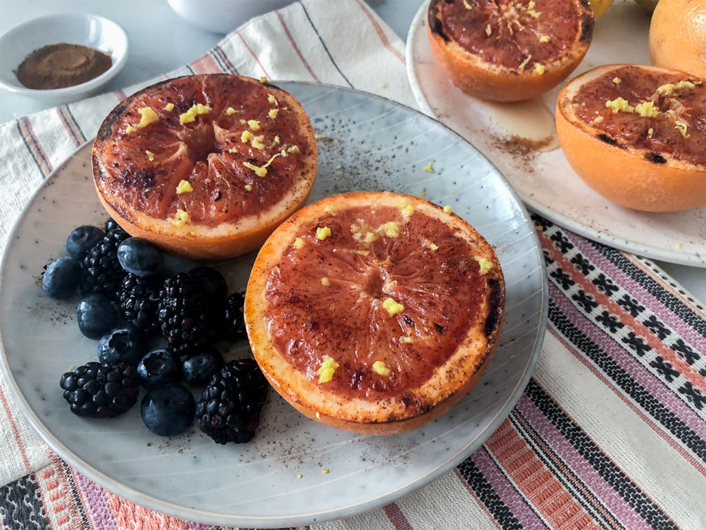 Broiled Grapefruit on plates topped with lemon zest, honey and cinnamon