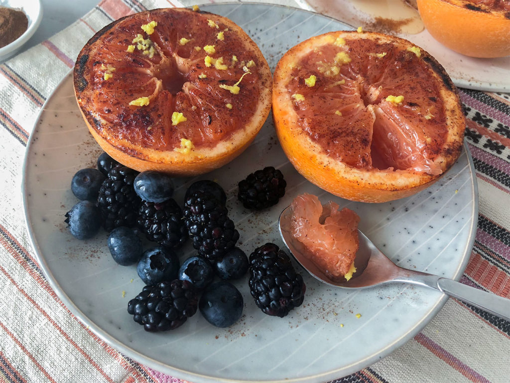 Broiled Grapefruit on plates topped with lemon zest, honey and cinnamon