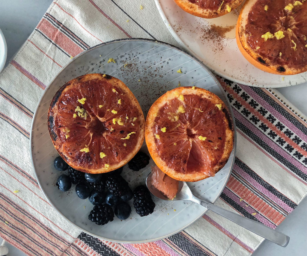 Broiled Grapefruit on plates topped with lemon zest, honey and cinnamon