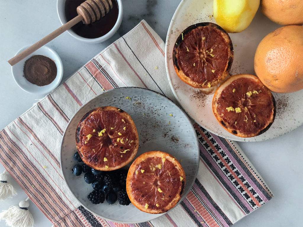 Broiled Grapefruit on plates topped with lemon zest, honey and cinnamon