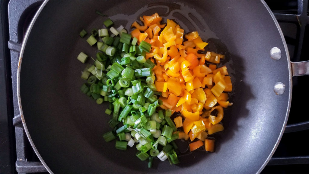 pepper and green onions satueing in a pan
