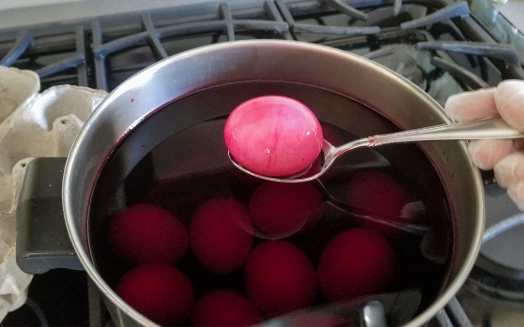 Eggs in red dye in a stock pot