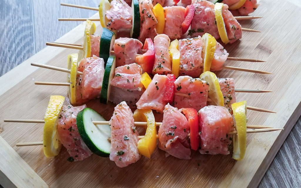 Greek Salmon Kebabs on a cutting board before grilling