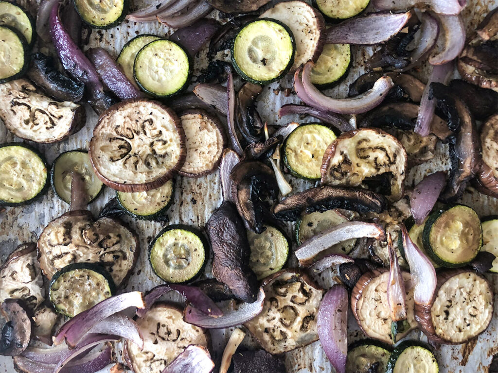 Oven roasted vegetables on a baking sheet lined with parchment paper