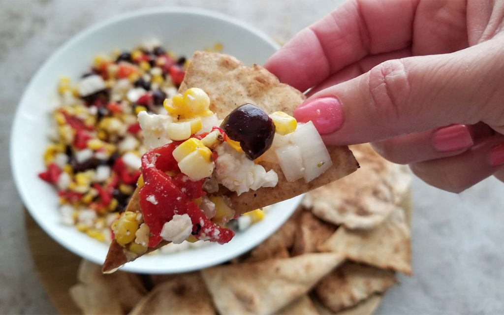 Grilled  Greek Corn Salsa in a bowl and on a homemade pita chip