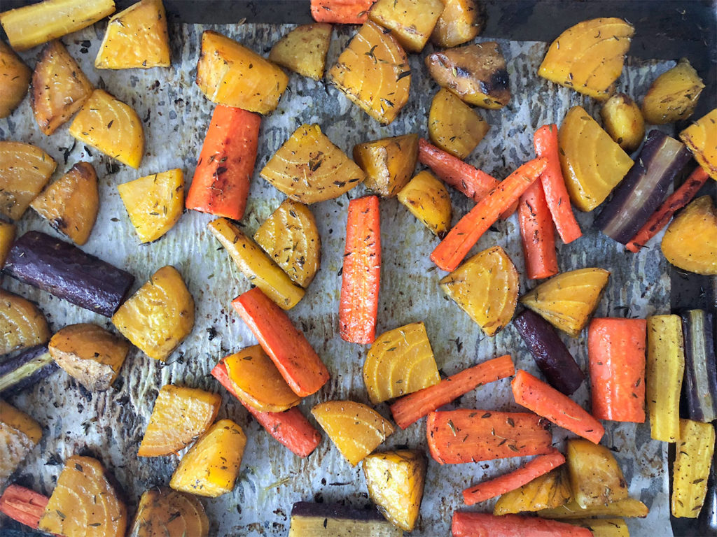 Roasted golden beets and rainbow carrots on a baking sheet
