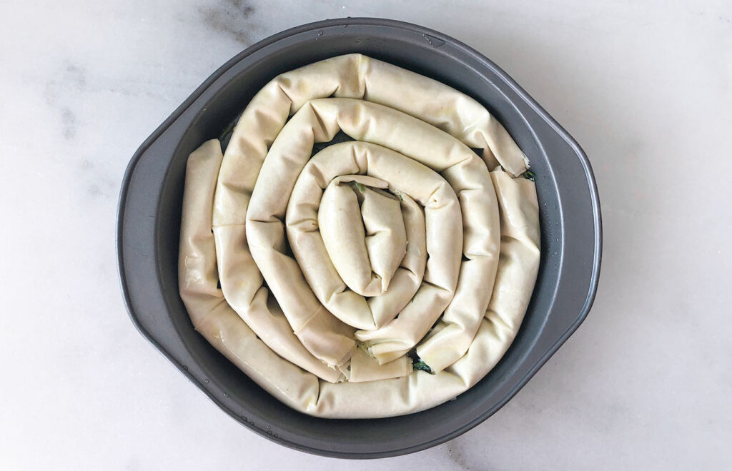 phyllo stuffed with spanakopita swirl mixture, roller and in a pan
