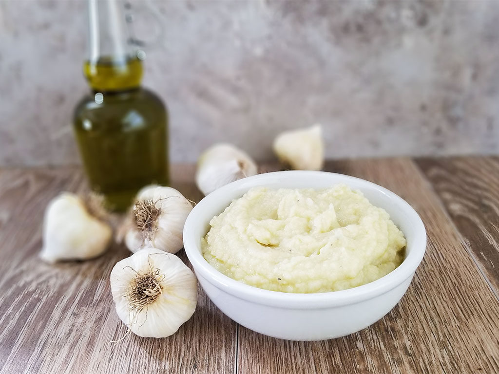 Skordalia in a bowl with garlic and olive oil