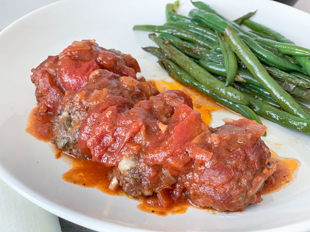 Greek Meatballs in Tomato Sauce with a side of green beans on a plate