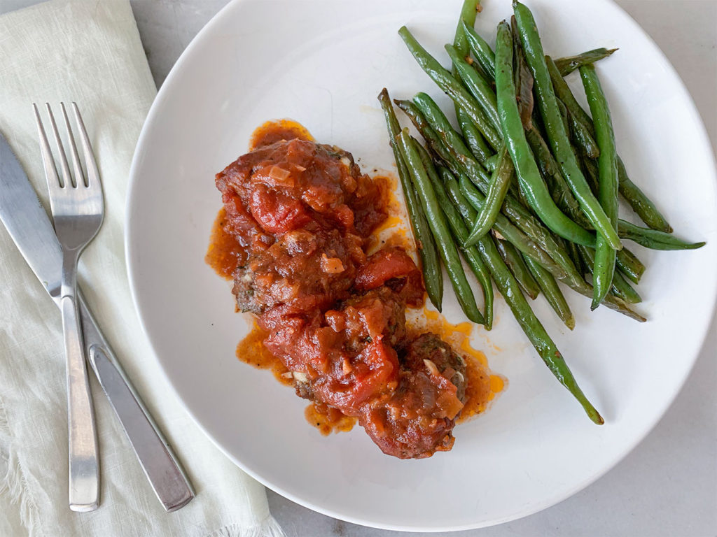 Greek Meatballs in Tomato Sauce with a side of green beans on a plate