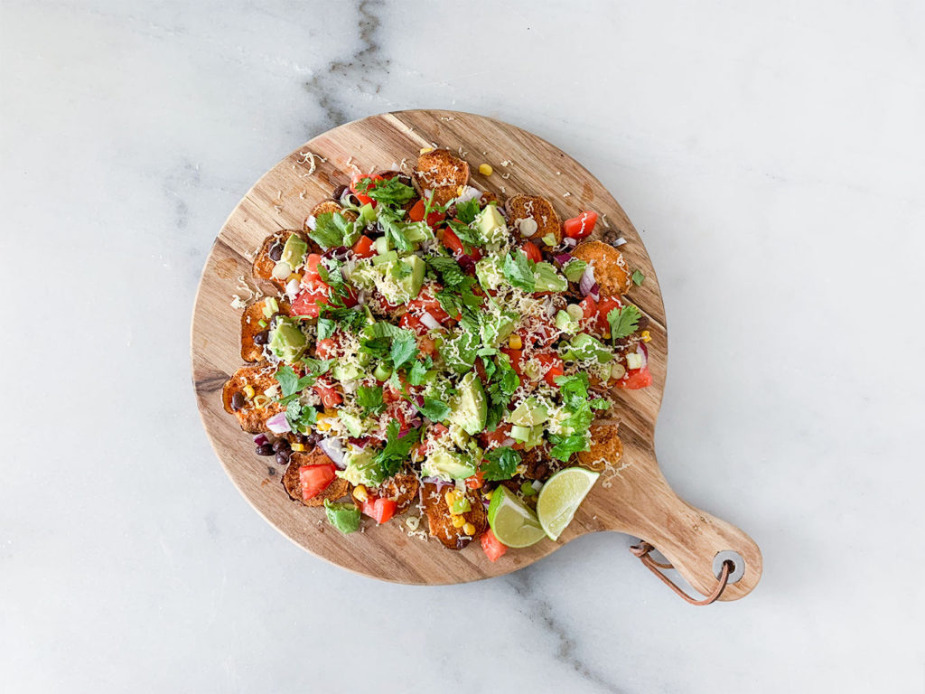 Sweet Potato Nachos assembled on a cutting board with limes