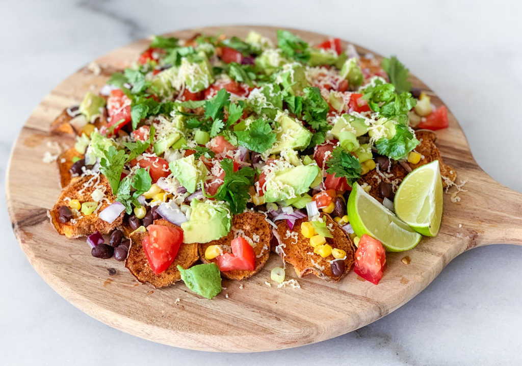 Sweet Potato Nachos assembled on a cutting board with limes