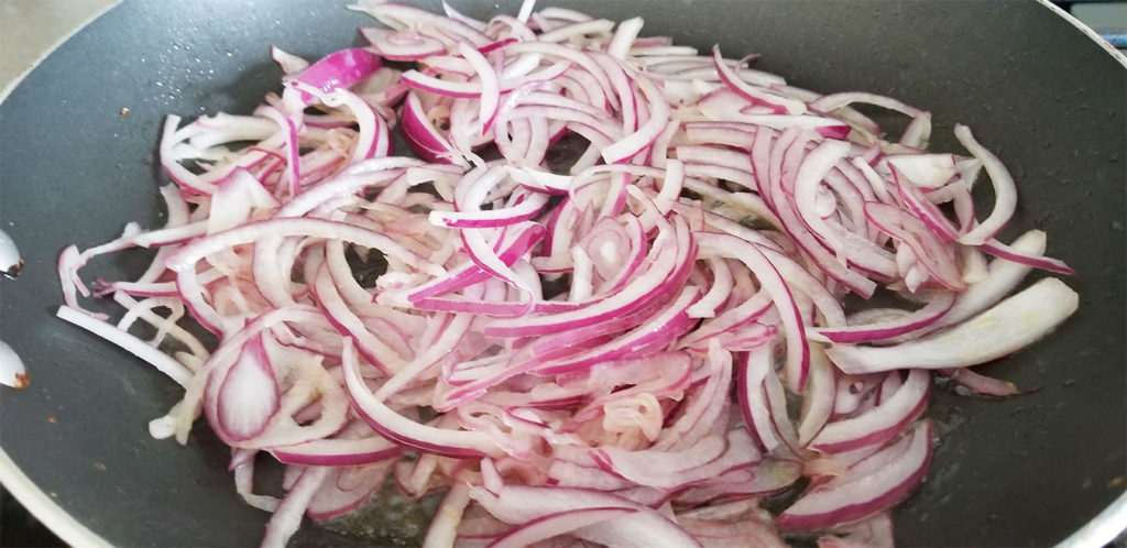sliced red onion in a sauté pan