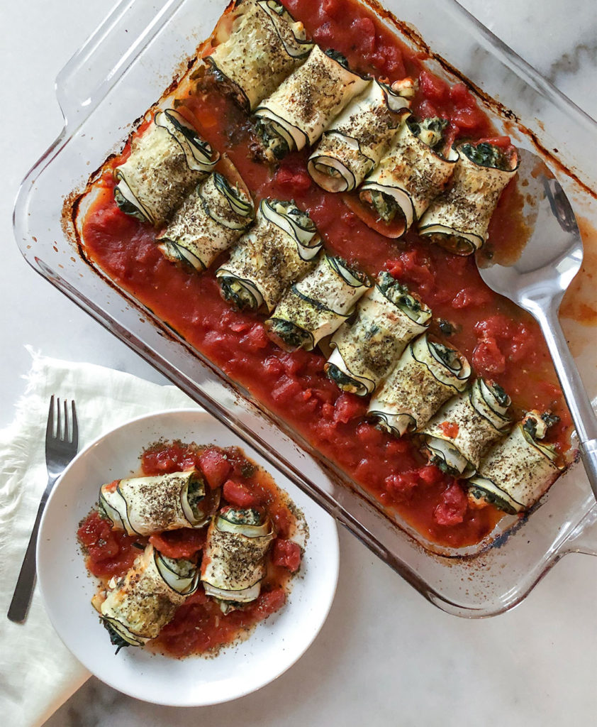 Spanakopita Stuffed Zucchini Roll-Ups in a baking dish and on a plate