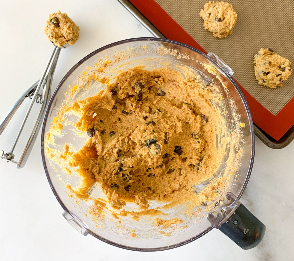 pumpkin cookie batter in a food processor and on a baking sheet