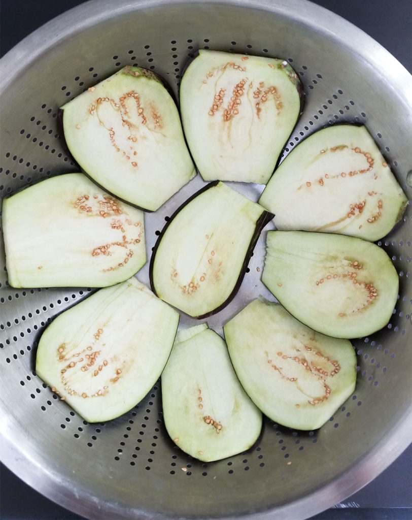 sliced eggplant in a colander 