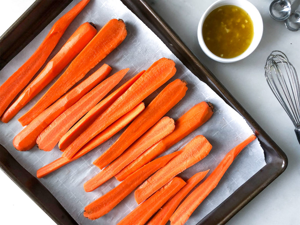 carrots cut in half on a baking sheet
