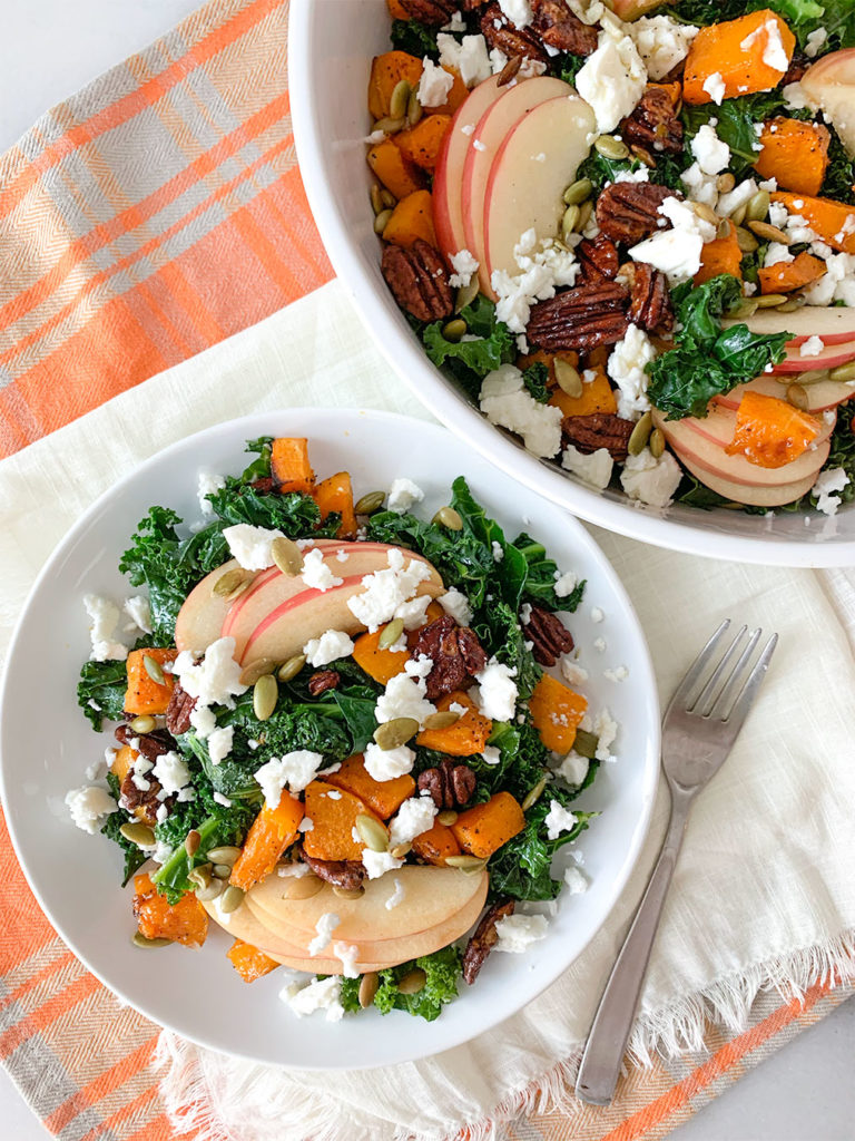 Warm Kale Salad with apples, pecans, feta cheese in a serving bowl and on a plate