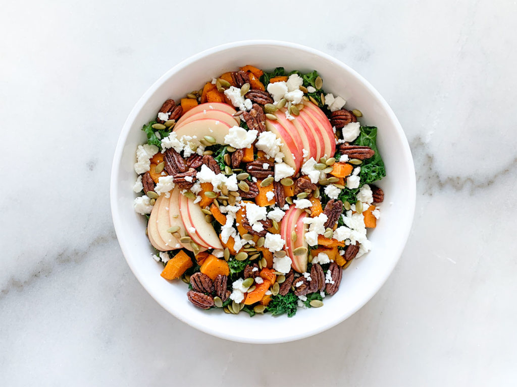 Warm Kale Salad with apples, pecans, feta cheese in a serving bowl