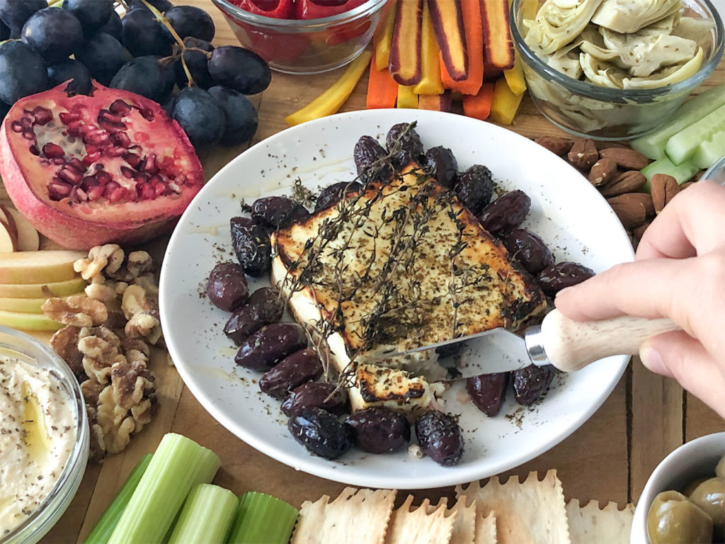 Baked feta and a variety of fruits and vegetables on a platter