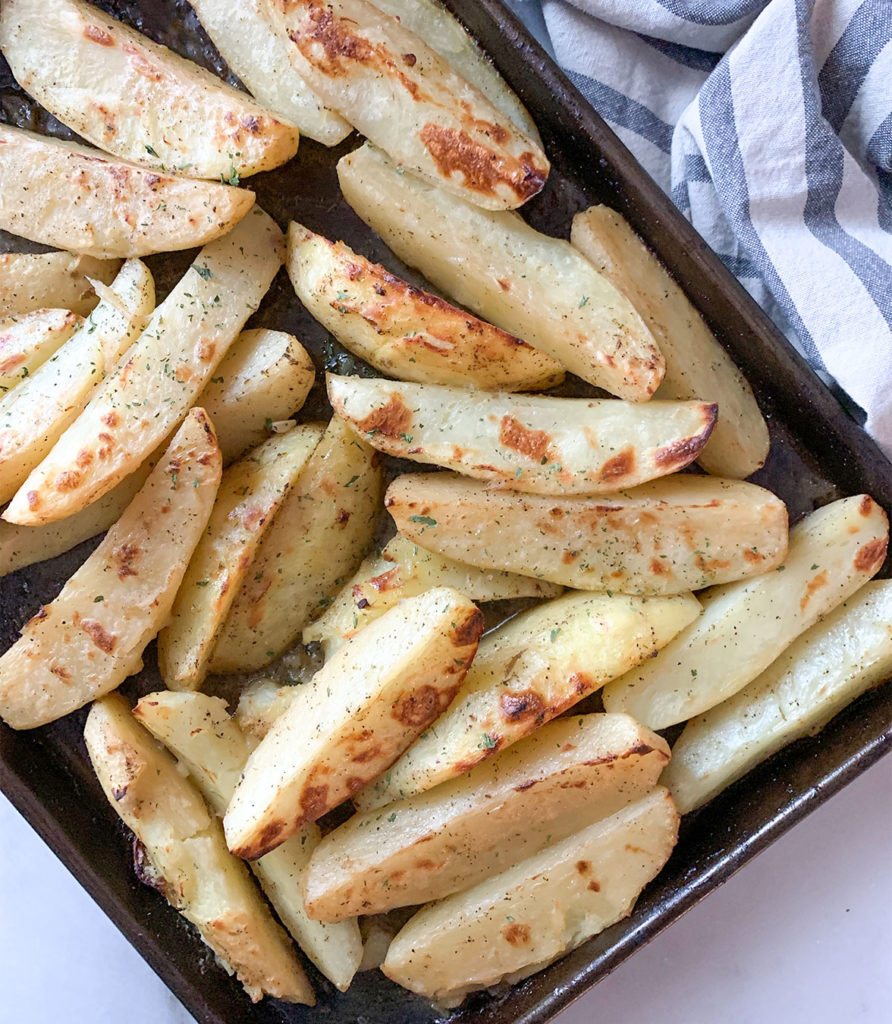 cooked lemon potato wedges on a baking sheet