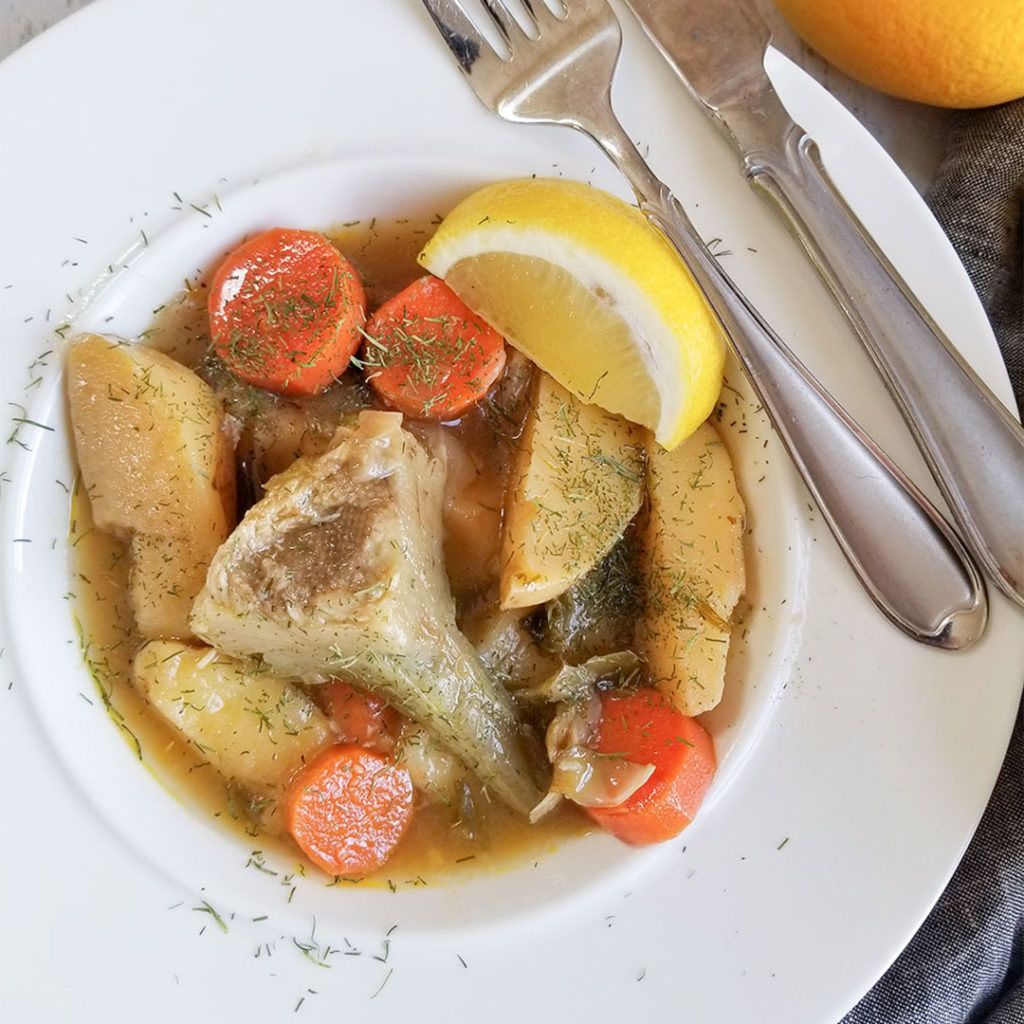Greek Artichoke Stew served in a bowl with a lemon wedge