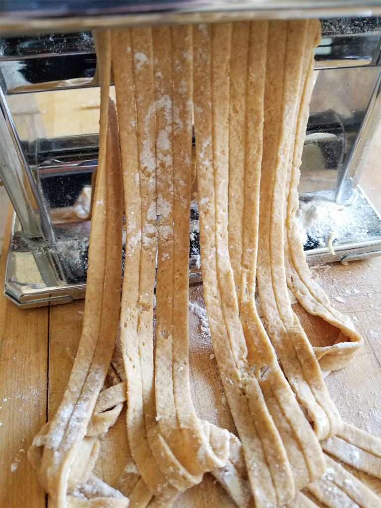 Homemade Wheat Pasta dough rolling through a pasta machine