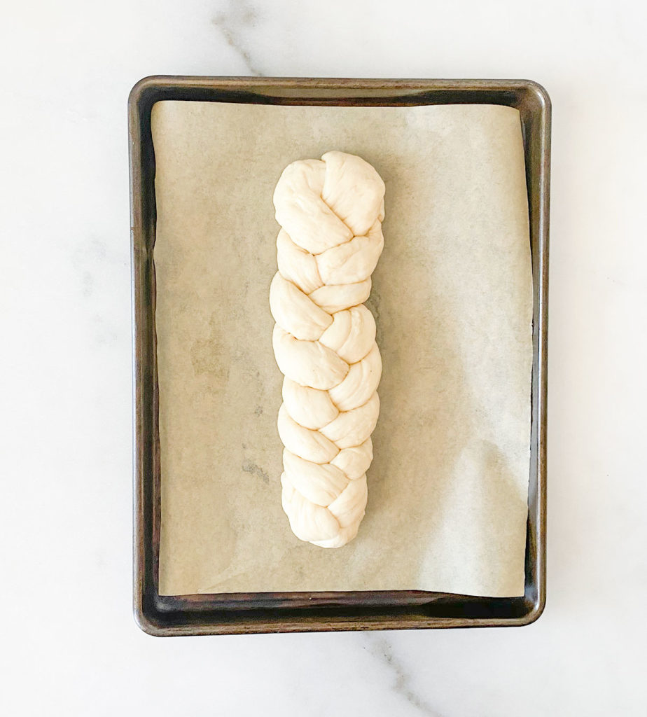 braided tsoureki dough on a baking sheet