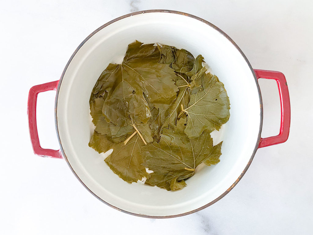 grape leaves lining the bottom of a stock pot