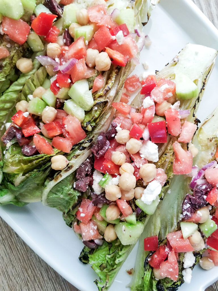 Grilled Romaine lettuce topped with a mediterranean salad