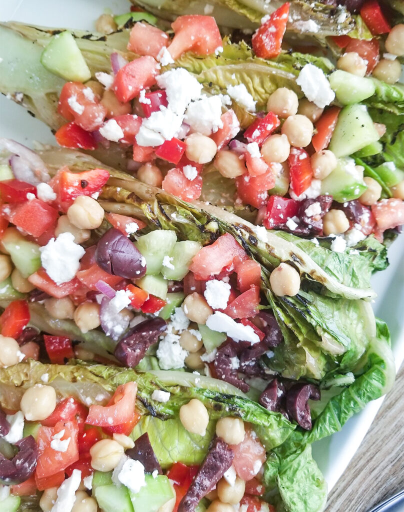 Grilled Romaine lettuce topped with a mediterranean salad