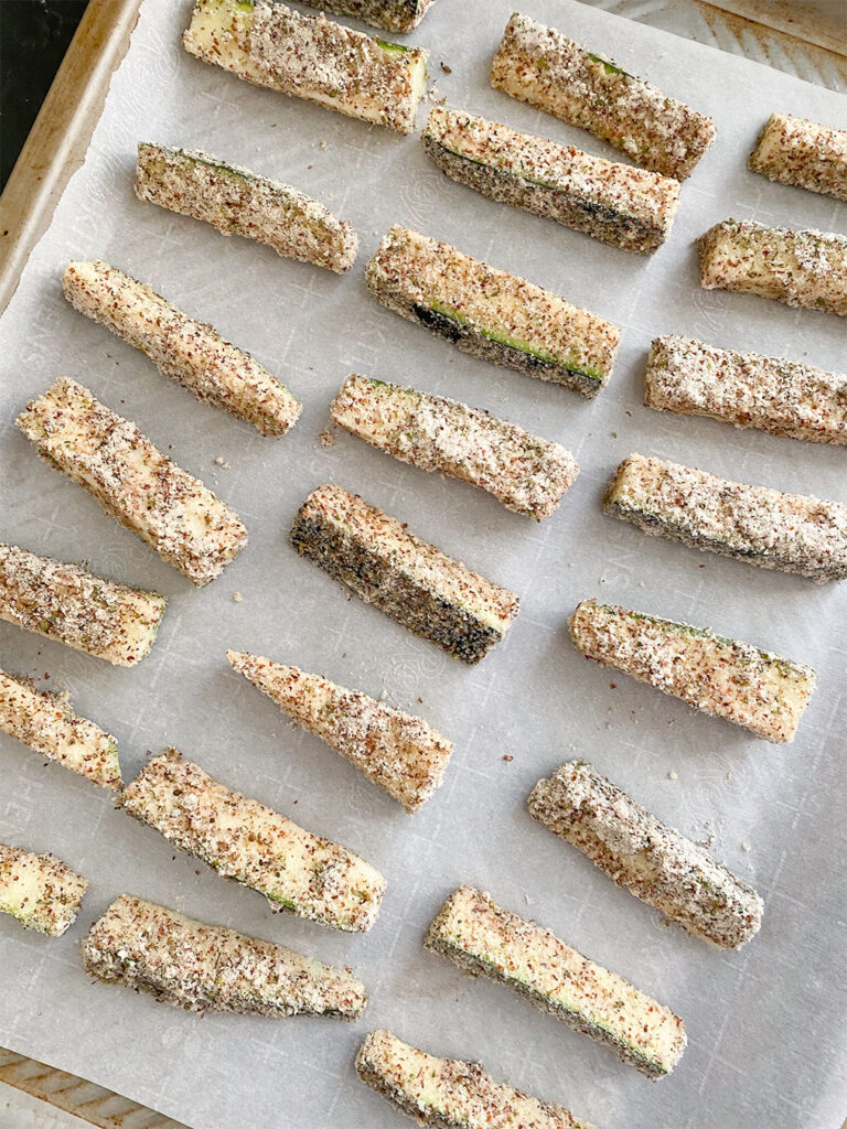 Zucchini match sticks in an almond flour coating ready to be baked