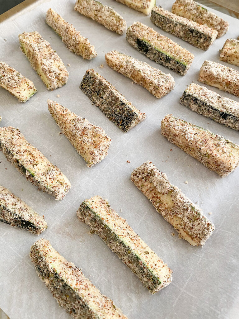 Zucchini match sticks in an almond flour coating ready to be baked