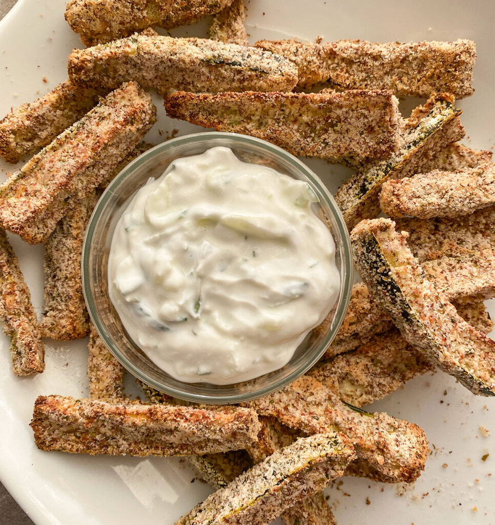 vegan tzatziki dipping sauce surrounded by crispy baked zucchini fries