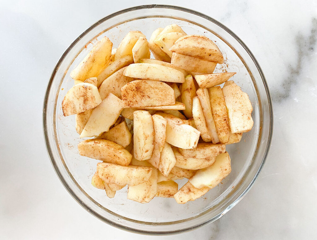 spiced apples in a bowl with cinnamon, nutmeg, maple syrup and vanilla extract