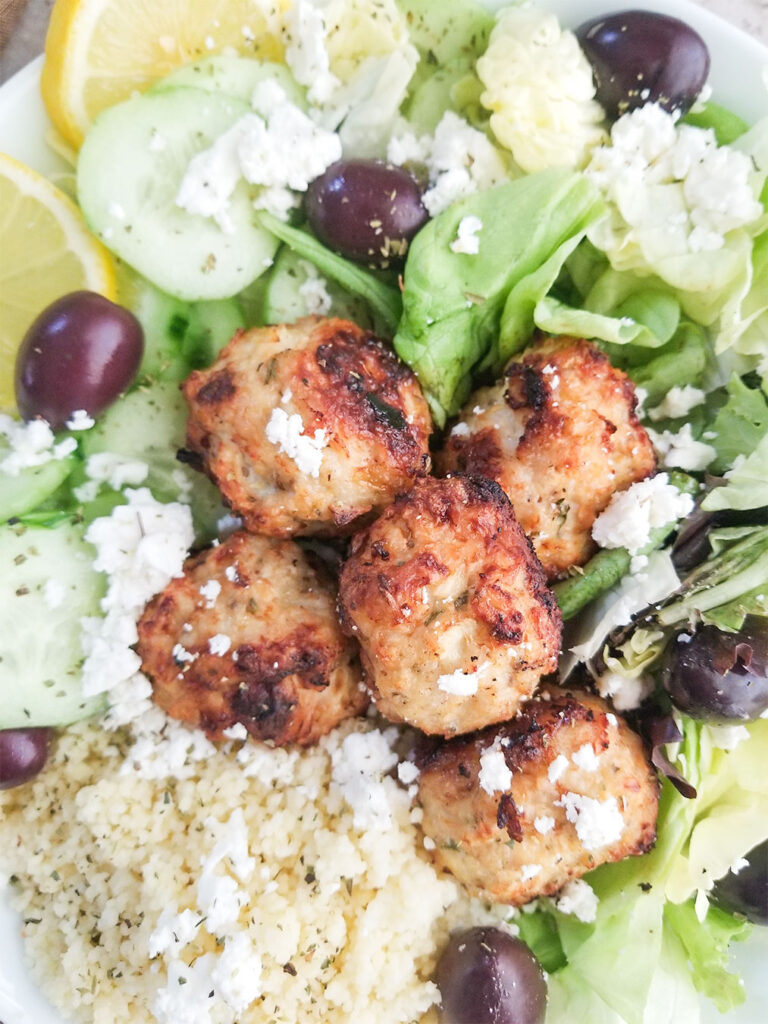 baked chicken meatballs on top of salad and couscous