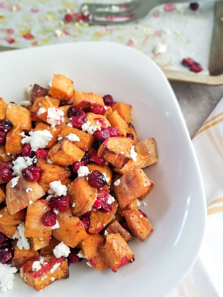 Roasted sweet potatoes with cranberries and feta cheese in a bowl