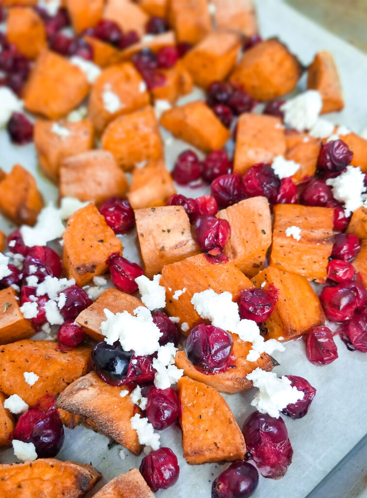 diced sweet potatoes, cranberries and feta cheese on a sheet pan