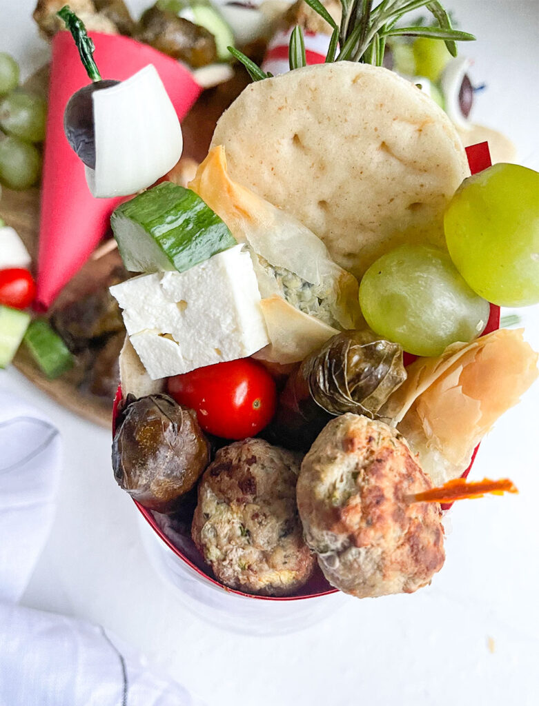 greek salad, turkey keftedes, stuffed grape leaves and spanakopita in a paper cone