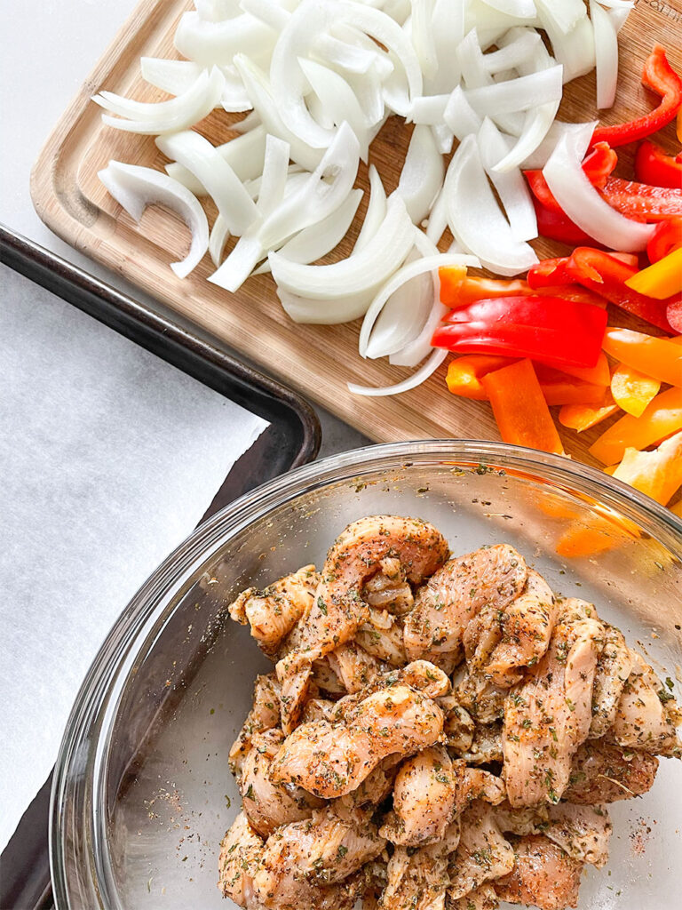 marinated chicken in a bowl and chopped onions and peppers