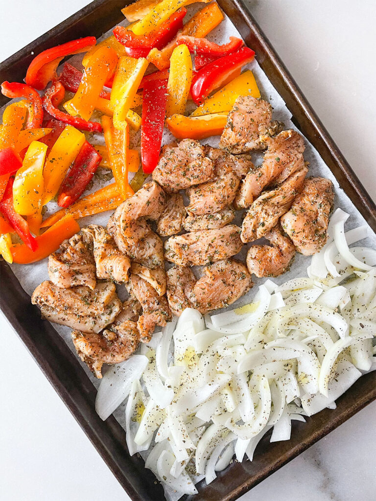 peppers, marinated chicken and onions on a sheet pan