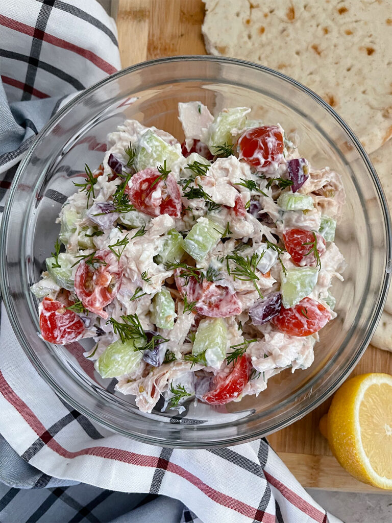 Greek chicken salad in a bowl with pita bread on the side